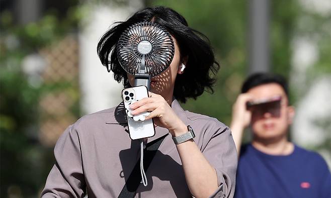 서울 종로구 거리에서 한 시민이 선풍기로 더위를 식히며 이동하고 있다. 뉴시스