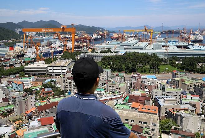대미 수출 관세 인하와 조선업 투자를 골자로 한 한미 무역 협상이 타결된 31일 한 시민이 경남 거제시 아주동 주거단지 너머로 한화오션 거제사업장 대형 크레인을 바라보고 있다. 정부는 미국 도널드 트럼프 행정부와 무역 협상 합의에는 한국이 제안한 조선업 협력안인 '마스가'(MASGA) 프로젝트가 가장 크게 기여했다고 밝혔다. 2025.7.31/뉴스1 ⓒ News1 윤일지 기자