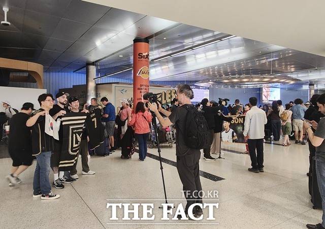 5일(현지 시간) LA 공항 톰 브래들리 입국장 로비에서 손흥민을 기다리던 한인팬들이 LAFC의 단기와 태극기 등을 펼쳐들고 기념촬영을 하고 있다./LA=미주헤럴드경제 제공