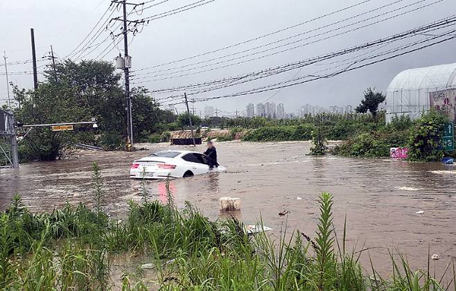 지난달 17일 곡교지하차도에 진입하다 급격히 불어난 물에 잠겨버린 승용차와 보닛에 올라가 구조를 기다리는 차주의 모습. 아산시 제공