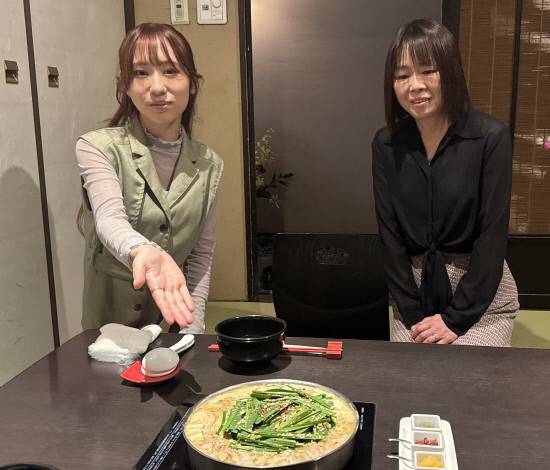 하카타 모츠나베 야마나카 아카사카점 나미세 사야 씨(왼쪽)와 치아키 토미야마(Chiaki Tomiyama) 본부 총무과장이 된장(미소) 맛 모츠나베를 설명하고 있다.