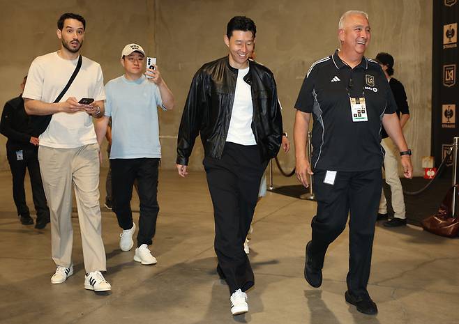 (손흥민이 7일(한국시간) LA FC 홈구장 주차장에 도착한 뒤 구단 관계자들과 함께 기자회견장으로 이동하고 있다)