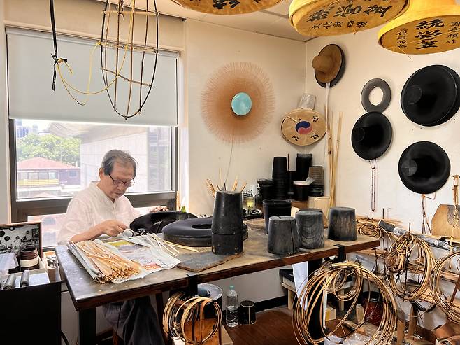 Chung Choon-mo demonstrates gat making during an interview with The Korea Herald on Monday at his studio at the Korea Heritage Agency in Samseong-dong, Seoul.  (Park Jun-hee/The Korea Herald)
