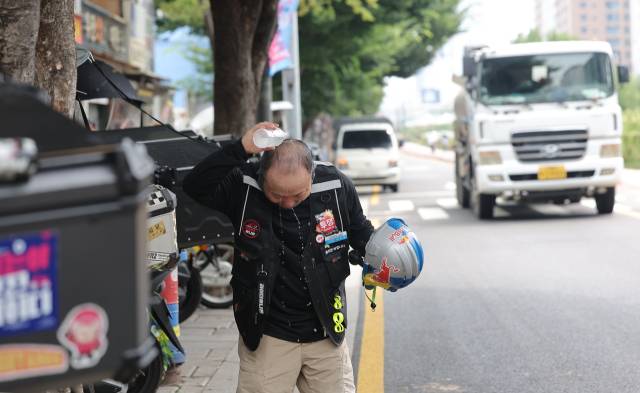 ▲폭염이 계속되는 30일 서울 시내에서 한 배달 노동자가 물을 뿌리며 더위를 식히고 있다. ⓒ연합뉴스