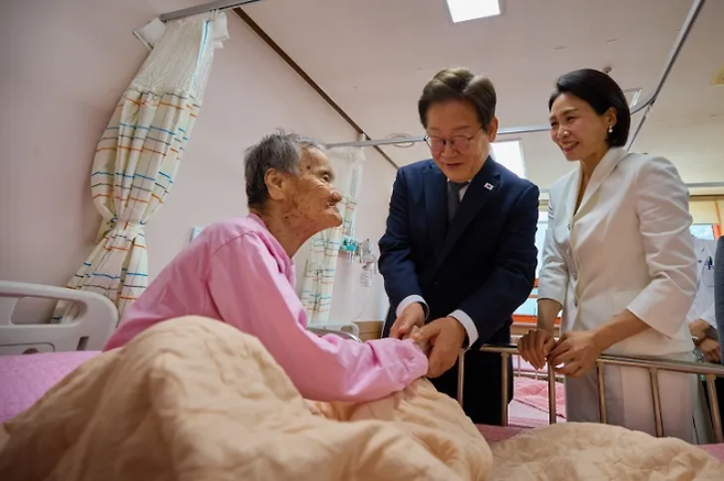 이재명 대통령이 대통령으로서는 처음으로 지난 6월 25일 김혜경 여사와 함께 전남 고흥군 국립소록도병원을 찾아 한센인 환자의 손을 잡고 위로하고 있다. 대통령실 제공