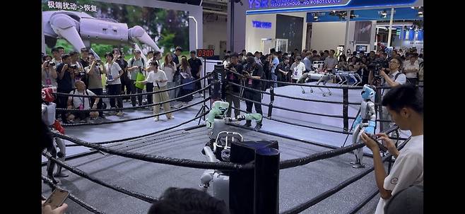 8일 중국 베이징에서 열린 세계로봇콘퍼런스(WRC)에서 중국 로봇기업 유니트리가 부스 안에 사각링을 마련하고 자사 휴머노이드 로봇 'G1'의 격투기 경기를 시연했다.  베이징 송광섭 특파원