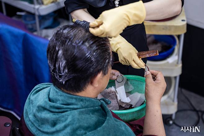 단골손님 윤성중씨가 파마 시술을 받으며 미용사에게 고무줄을 건네주고 있다. ⓒ시사IN 박미소