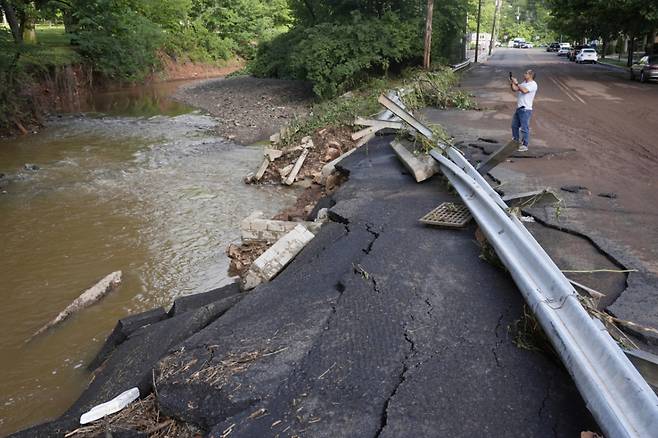 15일(현지 시간) 미 뉴저지주 노스플레인필드에서 한 남성이 개울 쪽으로 일부 무너져 내린 도로를 살펴보고 있다. 뉴저지주 일대에 지난 14일(현지시간) 밤 쏟아진 폭우로 차량이 급류에 휩쓸려 2명이 숨지고 도로와 가옥이 침수되는 등 피해가 발생했다. /AP=뉴시스