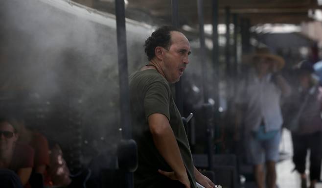 7월24일 그리스 전역에 고온이 예보된 가운데 아테네에서 한 남성이 더위를 식히기 위해 살수기 앞에 서 있다. ⓒEPA 연합