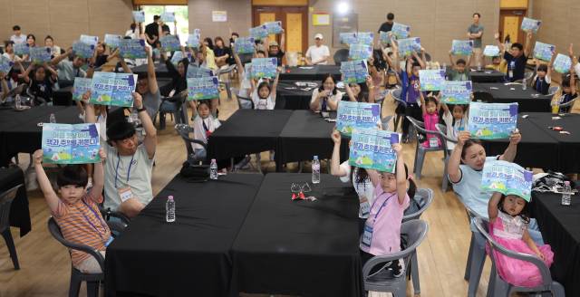 어린이들에게 독서의 재미를 전달하고 체험활동으로 창의력을 길러주기 위한 ‘2025 가족이 함께하는 독서 여름방학 캠프’가 9일 부산 금련산청소년수련원에서 열렸다. 개회식에서 참가 가족들이 책을 들고 기념촬영을 하고 있다. 이재찬 기자 chan@