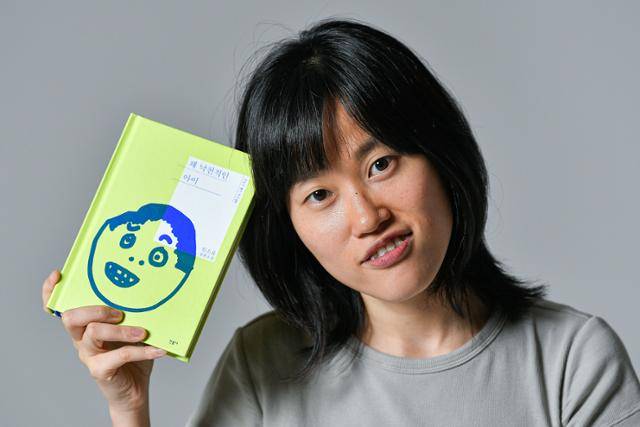 원소윤 작가가 8일 서울 중구 한국일보사에서 최근 출간한 장편소설 '꽤 낙천적인 아이'를 들고 미소 짓고 있다. 자전적 성장 소설답게, 작가의 가족 이야기가 축이다. 소설을 읽어 본 엄마는 "(넷플릭스 시리즈) '마이네임'보다 재미있다"고 했고, 광화문 교보문고에 책이 깔리는 첫날, 현장을 생중계한 오빠는 "모자 쓰고 가길 잘했다. 정말 많이 울고 웃었다"는 감상평을 남겼다. 남동균 인턴기자