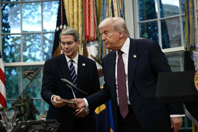 도널드 트럼프(오른쪽) 미국 대통령이 6일 미 워싱턴 백악관 집무실에서 스콧 베선트 재무장관에게 B-2 스텔스 폭격기 모형을 건네고 있다. 워싱턴=AFP 연합뉴스