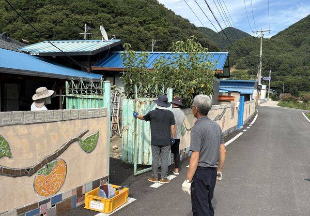 지난 2일 안양감리교회 장년부 성도들이 충남 논산 신기리2구 마을에서 대문 페인트칠 봉사를 하고 있다. 박지현 목사 제공