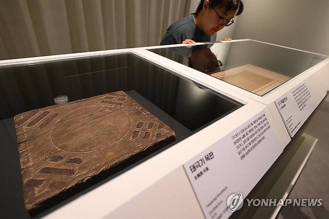 태극기목판과 독립선언서 (서울=연합뉴스) 강민지 기자 = 11일 서울 중구 덕수궁 돈덕전에서 열린 특별전 '빛을 담은 항일유산' 언론공개회에서 관계자가태극기 목판,  3ㆍ1독립선언서를 살펴보고 있다. 전시는 근대기 항일 독립유산을 통해 광복의 의미를 조명한다.   2025.8.11 mjkang@yna.co.kr