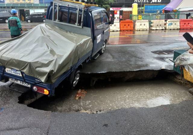12일 부산 사상구 감전동 부산새벽시장 정문 앞에서 대형 싱크홀이 발생해 트럭의 뒷바퀴가 빠져 위태로운 모습을 보이고 있다. 독자 제공