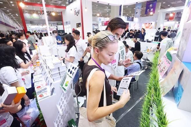지난 5월 서울 강남구 코엑스에서 열린 2025 서울국제화장품미용산업박람회 및 국제건강산업박람회를 찾은 외국인 바이어와 관람객들이 제품을 살펴보고 있다.(사진=연합뉴스)