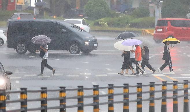 정체전선 영향으로 호우특보가 내려진 11일 오전 제주시 노형오거리 인근 거리에 우산을 쓴 시민들이 걸어가고 있다./뉴시스