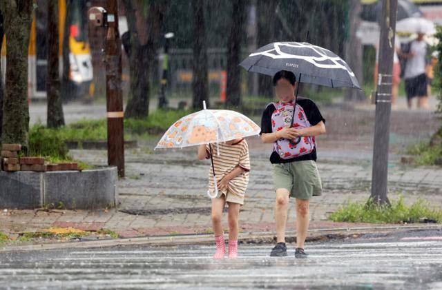 비가 내린 12일 광주 서구 상무지구에서 우산을 쓴 시민들이 조심스럽게 걷고 있다. 뉴스1