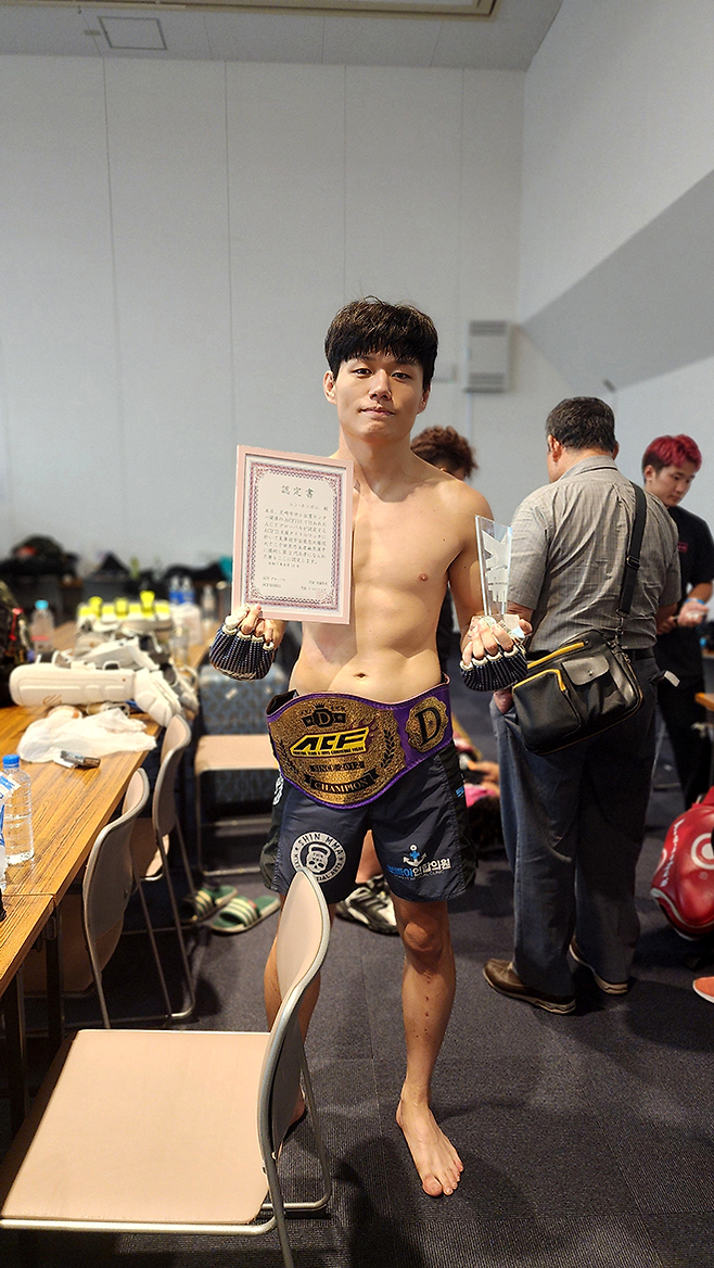 KMMA 웰터급 및 슈퍼라이트급 타이틀 도전자 출신 문홍범이 2025년 8월 일본 효고현 아마가사키시 주쇼키고센터에서 ACF 라이트급 챔피언 벨트를 감고 인증서와 트로피를 들며 기념 촬영을 하고 있다. 사진=스탠다드앤드프로그레스 스포츠에이전시 제공