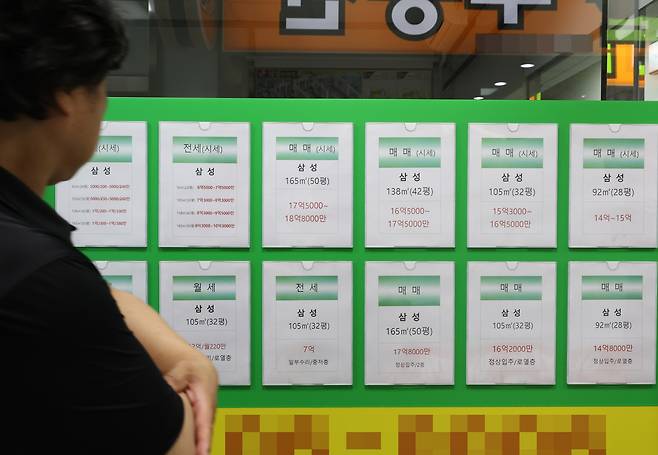 서울의 한 공인중개사무소 앞에 붙여진 매물 정보를 한 시민이 살펴보고 있다. 서울 집값 상승으로 신생아 특례대출을 받은 차주 중 서울에서 매수한 이는 단 7%로 집계됐다.  [연합]