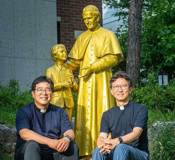 살레시오 청소년센터 입구의 돈보스코 성인 곁에 앉은 황철현(오른쪽), 최남식 신부. 이탈리아 성인 돈보스코는 아이를 사랑으로 키워야 한다는 일념으로 수도회를 세웠다. 아프리카 수단에서 학교를 세우고 봉사를 한 故이태석 신부도 살레시오 수도회 소속이다.