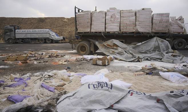 가자 지구 국경 근처에 13일(현지시각) 구호품을 실은 트럭이 서 있다. 포장이 뜯겨지고 손상된 구호품이 길에 흩어져있다. 가자/AP 연합뉴스