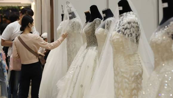 웨딩박람회에서 예비 신랑 신부들이 웨딩드레스를 둘러보고 있다. [사진=연합뉴스]