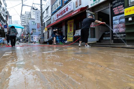 13일 오후 서울 은평구 연신내역 인근 상가 거리에서 상인들이 폭우로 인해 더러워진 거리를 청소하고 있다. 뉴스1