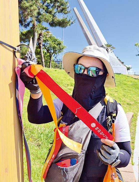 색 바랜 해파랑길 리본을 교체 중인 김윤옥 지킴이.