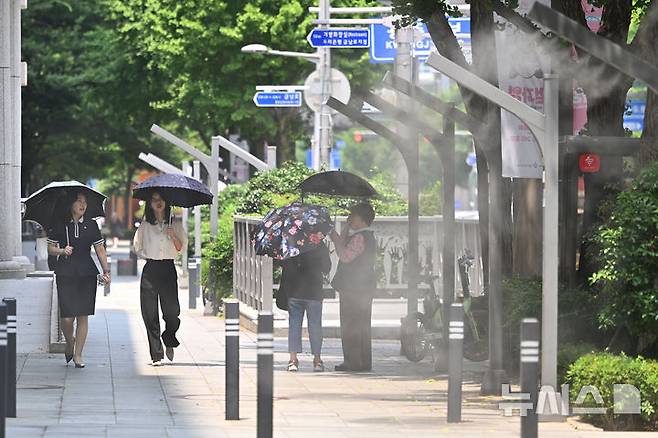 [광주=뉴시스] 이영주 기자 = 광주지역에 폭염특보가 이어지고 있는 8일 오후 광주 동구 금남로에서 시민들이 양산을 쓴 채 쿨링포그 주변을 걷고 있다. 2025.07.08. leeyj2578@newsis.com