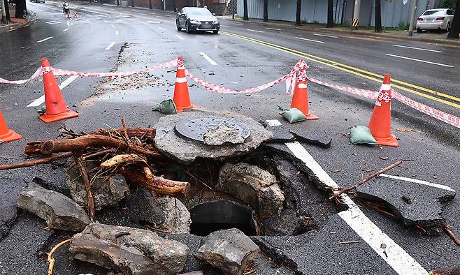 13일 서울 종로구 한 도로의 맨홀이 빗물 역류로 파손돼 있다. 연합뉴스