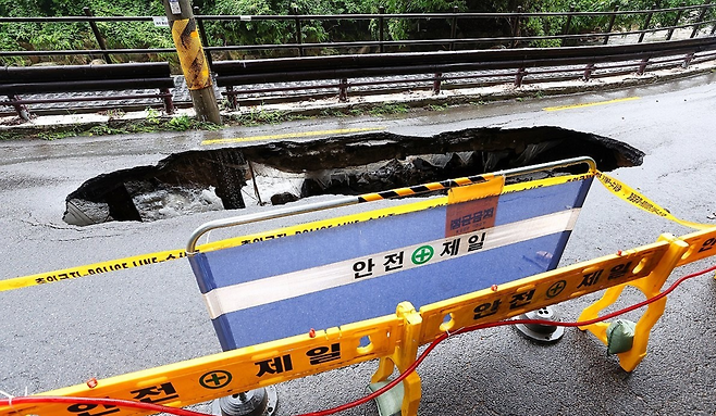 서울 곳곳에 호우주의보가 내린 13일 집중호우로 인한 땅 꺼짐 현상이 발생한 서울 강북구 북한산국립공원 내 선운각 앞 도로에 시민들의 접근을 막는 펜스가 설치돼 있다.