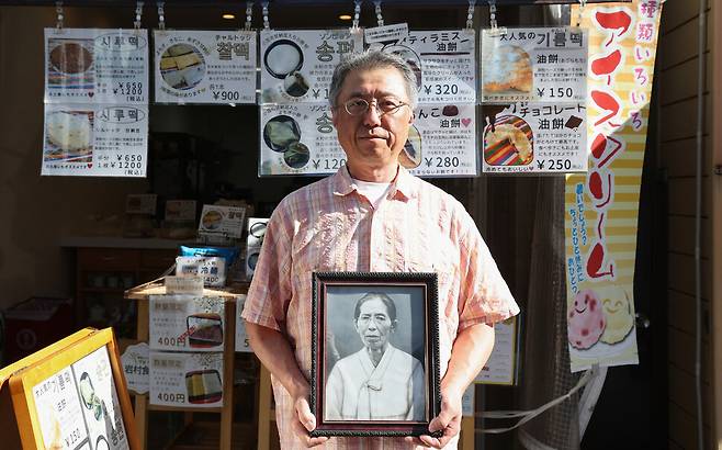 홍성민씨가 지난달 27일 오후 일본 오사카 코리아타운 이와무라식품 앞에서 할머니 김양능씨의 영정을 들고 있다. 이곳은 홍씨가 할머니에게서 제조법을 전수받아 전통 제주식 떡을 만들어 파는 가게로, 할머니는 이곳 2층에서 생활하다가 1973년에 돌아가셨다. 오사카/김영원 기자 forever@hani.co.kr