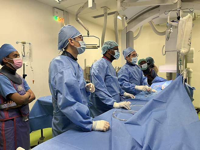 심도자중재술 진행 중, 김기범 교수가 현지 의료진 곁에서 시술을 보조하며 필요한 기술적 지침을 전하고 있다.