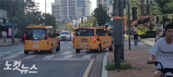 서로 어긋난 출입구에서 학원차량 등이 드나들고 있는 가운데, 주민들이 횡단보도를 건너고 있다. 박창주 기자
