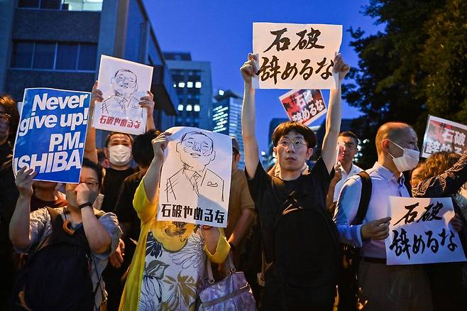 7월25일 일본 도쿄 총리 관저 인근에서 “이시바 그만두지 마”라고 적힌 피켓을 든 시위대.ⓒAFP PHOTO
