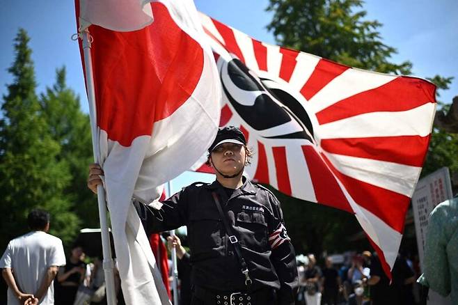 15일 일본 도쿄 야스쿠니신사에서 한 일본인이 군국주의 상징인 욱일기를 들고 서 있다. AFP 연합뉴스
