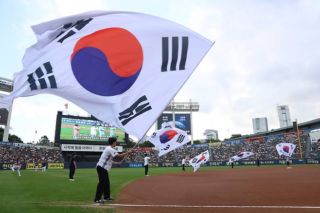뮤지컬 배우 윤현선, 김요한, 최진수, 장진수가 15일 잠실야구장에서 열린 기아 타이거즈와 두산 베어스의 경기 전 기미독립선언서를 낭독하는 등의 공연을 펼치는 동안 그라운드 위에서 태극기가 흩날리고 있다. 두산 베어스 제공