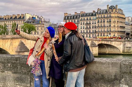 센강변에서 바게트를 들고 사진을 찍는 관광객.