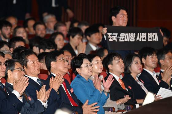 송언석 국민의힘 비상대책위원장 겸 원내대표와 김선민 조국혁신당 대표 권한대행이 15일 서울 세종문화회관에서 열린 제80주년 광복절 경축식에서 나란히 앉은 가운데 뒷줄 안철수 국민의힘 의원이 조국 전 조국혁신당 대표의 사면에 반대한다는 취지의 항의 시위를 하고 있다. 조국혁신당은 국민의힘에 대한 정당해산심판 청구를 주장하고 있다. 대통령실사진기자단