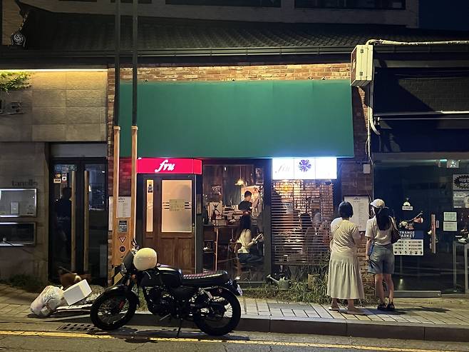 People look at the menu posted in front of Fru, a Japanese izakaya in Jongno-gu, Seoul. (Kim Jae-heun/The Korea Herald)