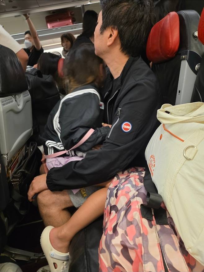Lee Mi-hyun's husband and daughter wait inside the plane after its emergency landing at Gimpo Airport on Wednesday, while passengers stand nearby asking crew members about the situation. (Courtesy of Lee)