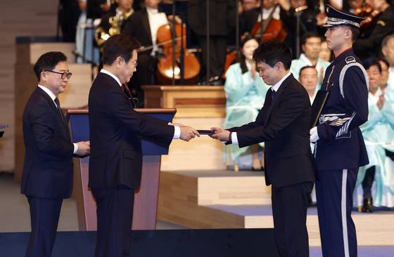 President Lee Jae Myung, left, presents the Order of Merit for National Foundation to a descendent of an independence activist during a ceremony marking the 80th Liberation Day at the Sejong Center for Performing Arts in Jongno District, central Seoul, on Aug. 15. [JOINT PRESS CORPS]