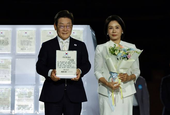 이재명 대통령과 김혜경 여사가 15일 서울 세종대로 광화문광장에서 열린 제21대 대통령 국민임명식 '광복 80년, 국민주권으로 미래를 세우다' 행사에서 국민 대표 80인으로부터 '빛의 임명장'을 받은 뒤 감사 인사를 하고 있다. 연합뉴스