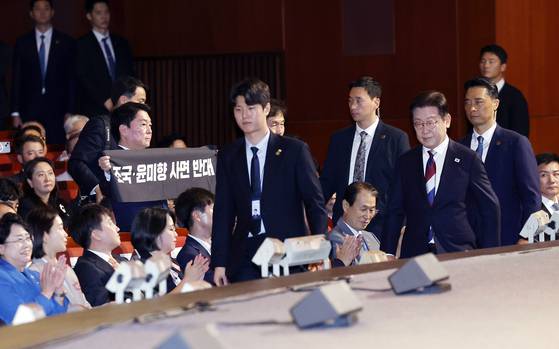 국민의힘 안철수 의원이 15일 서울 세종문화회관에서 열린 80주년 광복절 경축식에서 이재명 대통령이 경축사를 마치고 자리로 향할 때 '조국·윤미향 사면 반대'라는 문구가 적힌 펼침막을 들어보이고 있다. 뉴시스