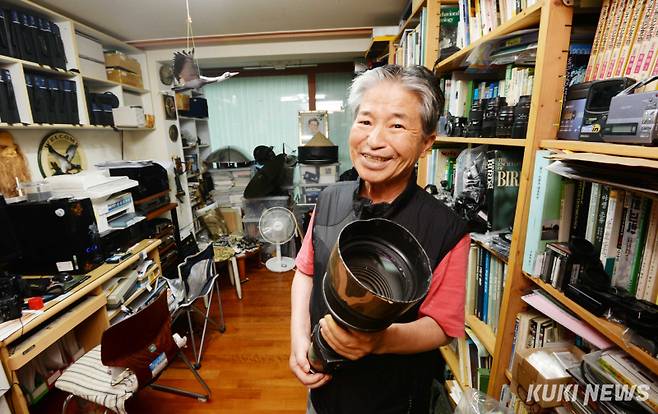 지난 2014년 고 윤무부 교수가 그의 휘경동 자택 연구실 겸 집필실에서 조류 촬영을 위한 초망원렌즈를 들어보이며 활짝 웃고 있다. 윤 교수는 전국을 돌아다니며 길에다 뿌린 돈과 장비 구입비를 합하면 집을 몇채는 구입했을 거라고 했다.