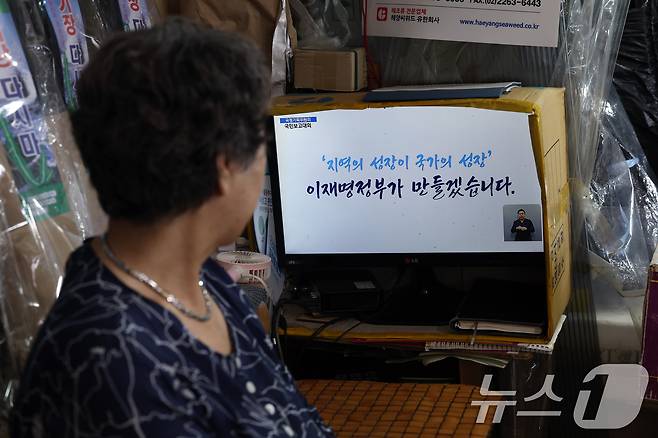 13일 오후 서울 도심의 한 전통시장에서 상인이 국정기획위원회 국민보고대회 '국민이 주인인 나라 함께 행복한 대한민국’ 생중계를 지켜보고 있다. 2025.8.13/뉴스1 ⓒ News1 박정호 기자