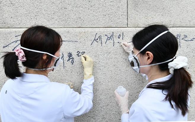 지난 11일 국립고궁박물관 유물과학과 관계자들이 서울 경복궁 광화문 석축에 남은 낙서를 제거하고 있다. 연합뉴스