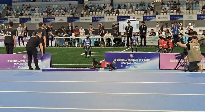[베이징=뉴시스] 박정규 특파원 = 15일 오전 '2025 세계휴머노이드로봇운동회'가 열린 중국 베이징 국가스피드스케이팅경기장에서 진행된 로봇축구 경기 도중 한 로봇이 펜스를 넘어뜨린 채 쓰러져 있다. 2025.08.15