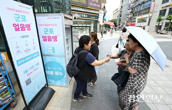 무더운 날씨가 이어진 18일 오후 군포시 산본로데오거리에 설치된 무인 냉장고 ‘군포 얼음땡’에서 시민들이 물을 가져가고 있다. 2025.8.18 /최은성기자 ces7198@kyeongin.com